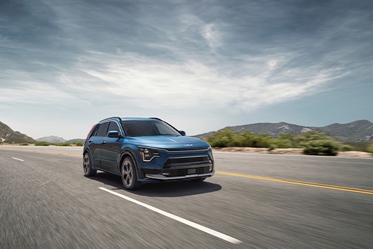 blue Kia Niro Plug-in Hybrid SUV driving on a highway