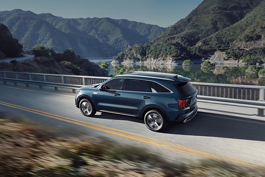 blue Kia Sorento hybrid driving over a bridge