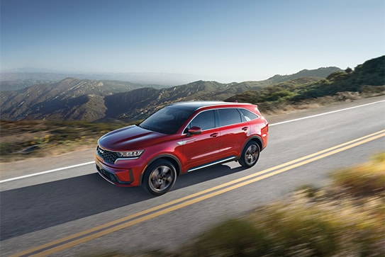 red Kia Niro Hybrid SUV driving on a highway