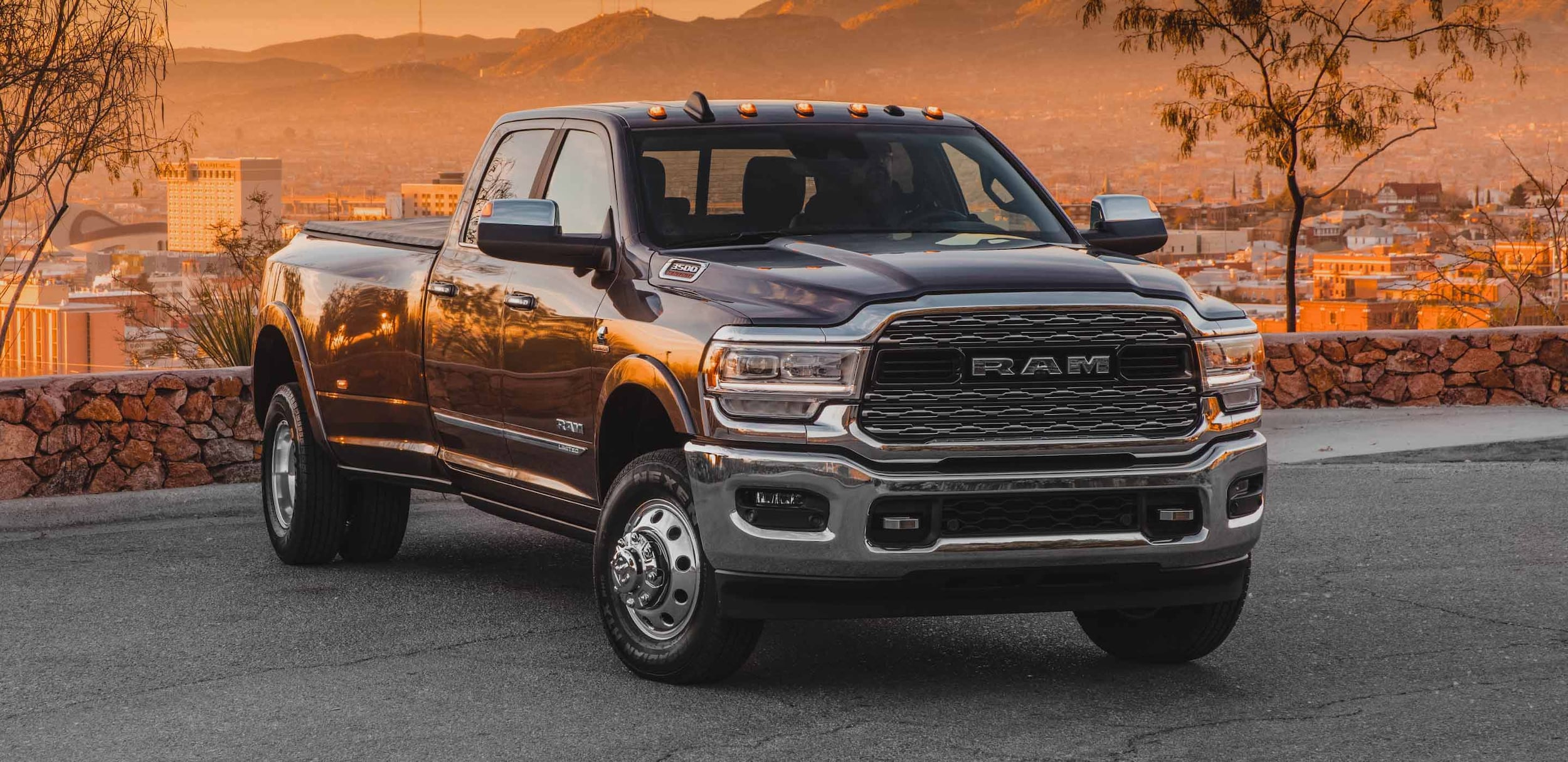 brown Ram 3500 truck parked in front of a housing area at sunset