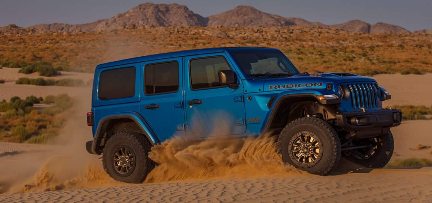 blue Jeep Wrangler 4xe cornering on a sand dune