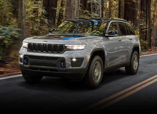 gray Jeep Grand Cherokee driving through a forested area