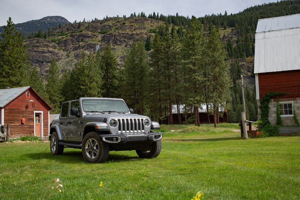 gray Jeep Wrangler Unlimited SUV parked near a grassy hill