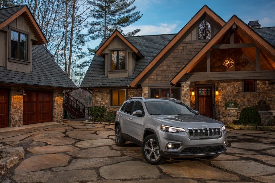 gray Jeep Cherokee SUV parked in front of a ski lodge