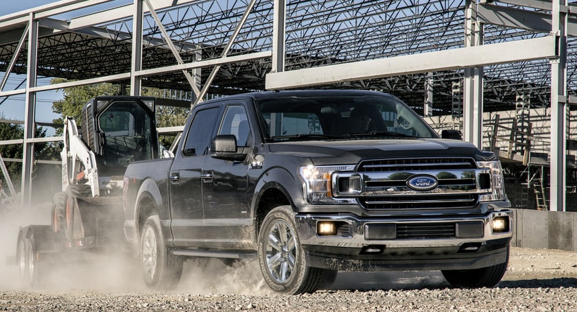black Ford F150 truck kicking up dust on a construction site
