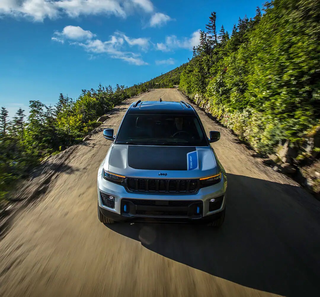 grey and black Jeep Grand Cherokee 4xe hybrid SUV driving on a forest trail
