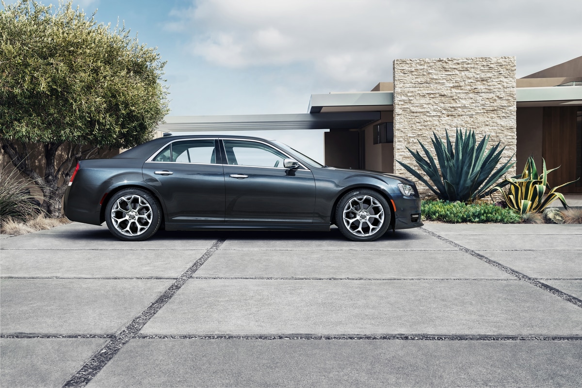 blue Chrysler 300 sedan parked in front of a modern home