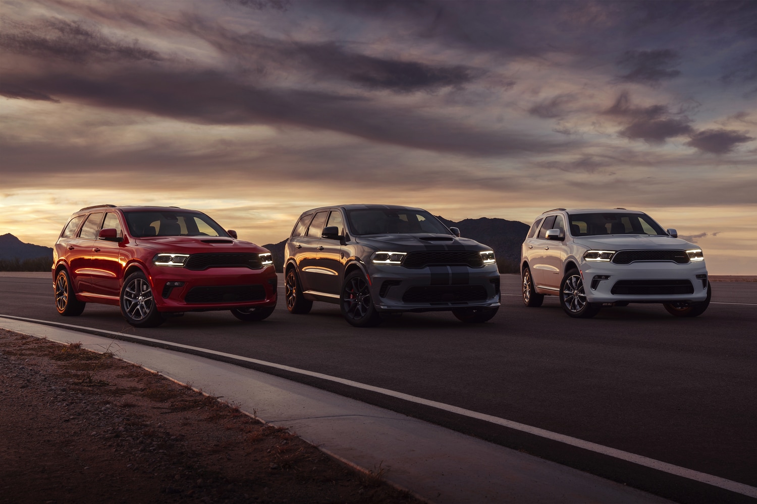 red, gray, and white Dodge Durango lineup sitting on a runway at sunset