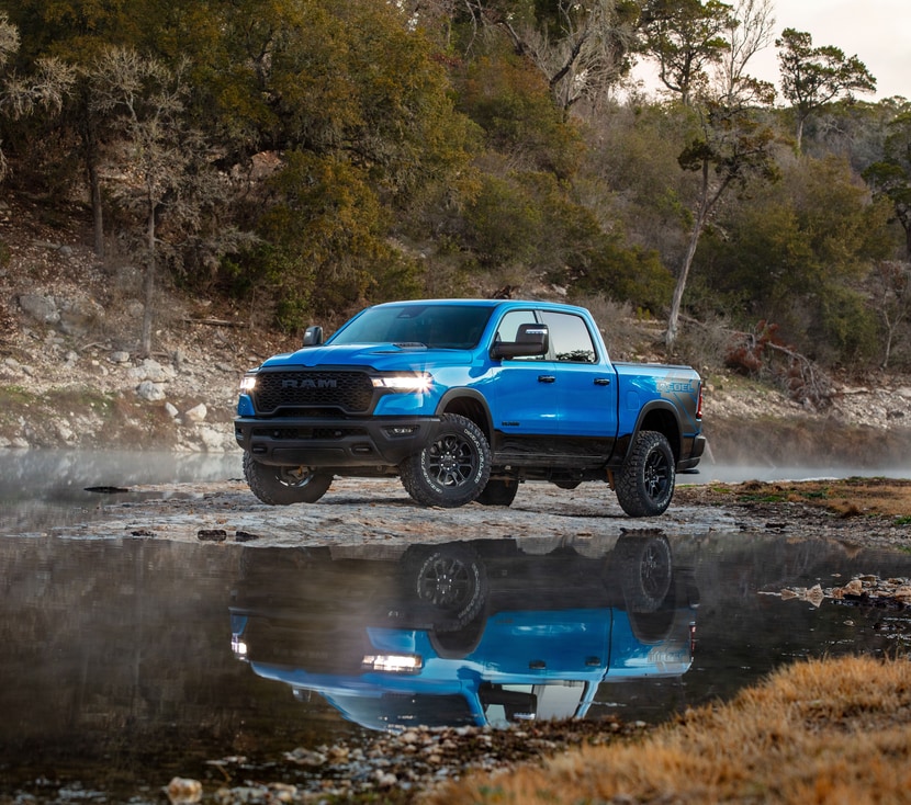 2025-RAM-1500-Rebel-CrewCab-Trucks.png blue Ram 1500 parked in a creek with the truck's reflection underneath