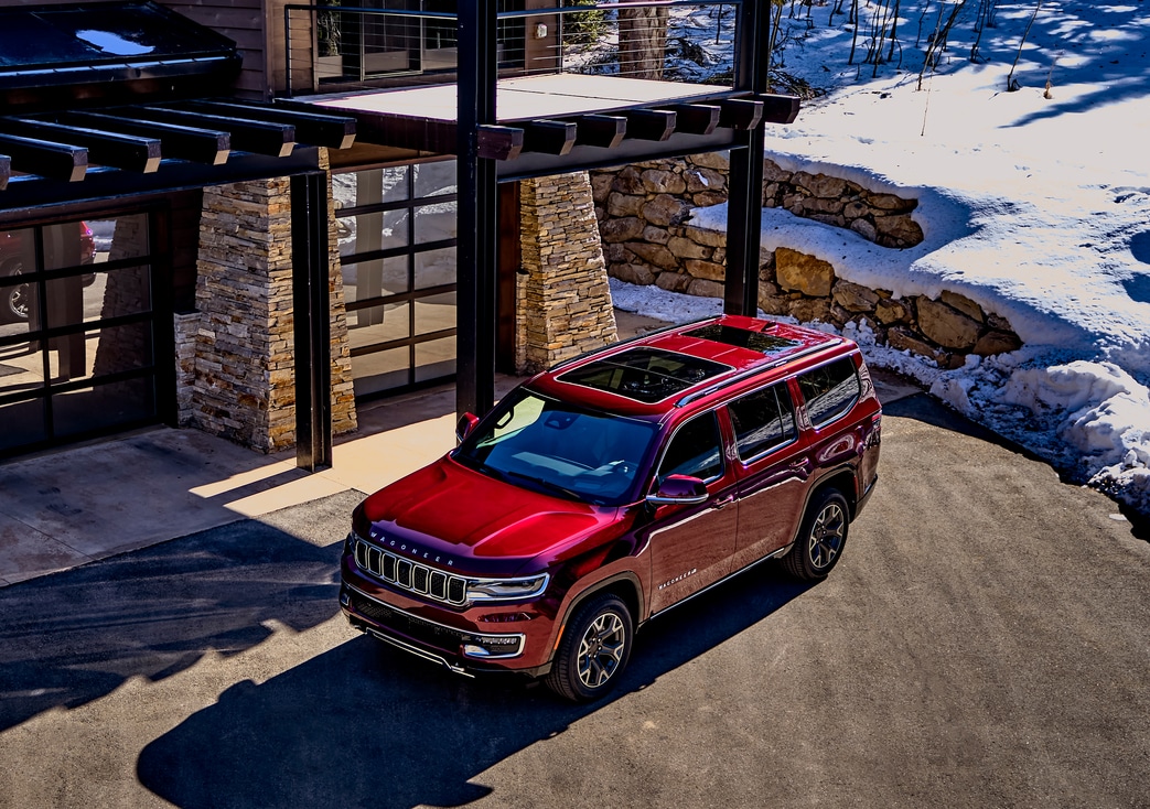 2024-Jeep-Wagoneer-SeriesII-SUV-L04.png top view of a red Jeep Wagoneer parked next to a snowy lodge