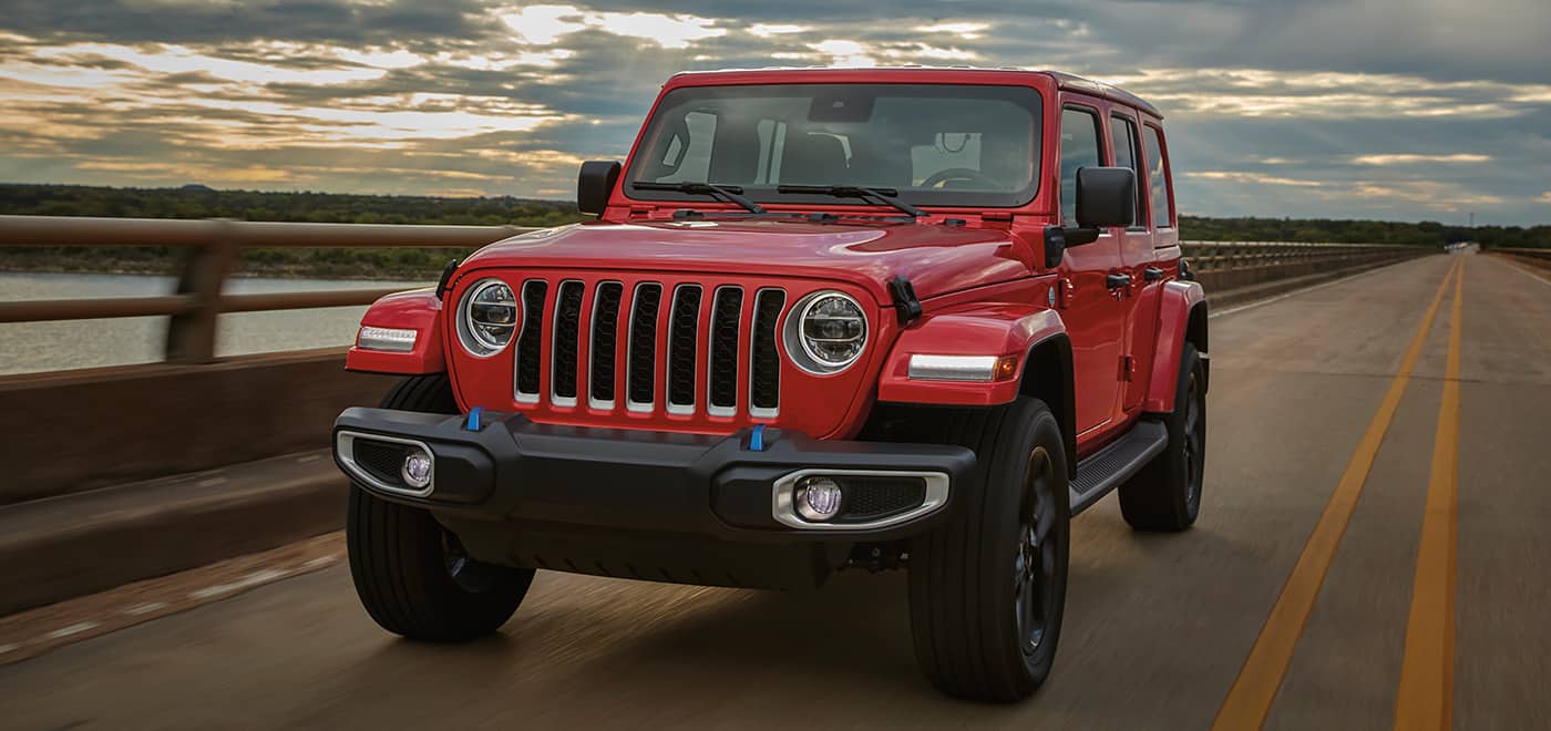 red Jeep Wrangler SUV driving down a highway