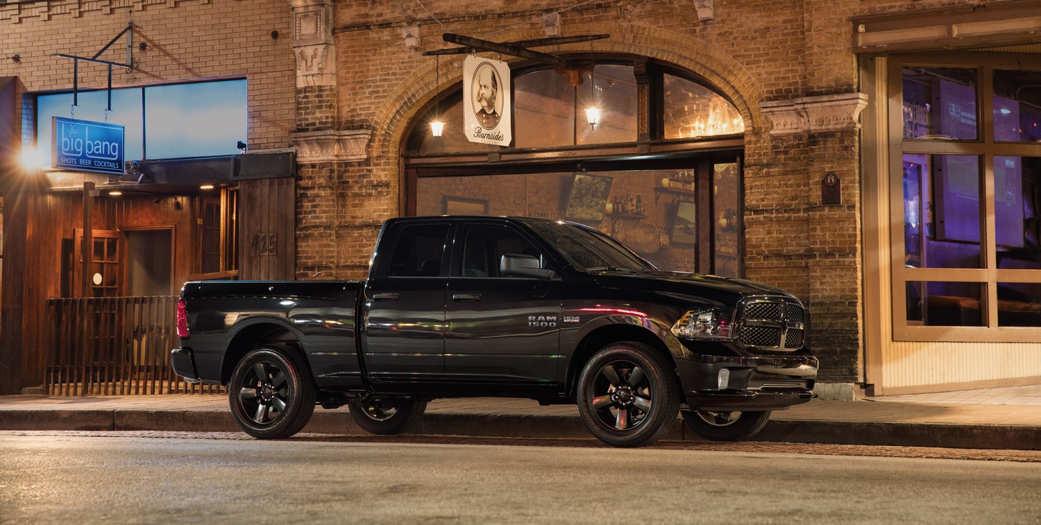 black Ram 1500 truck parked in front of a brightly lit bar