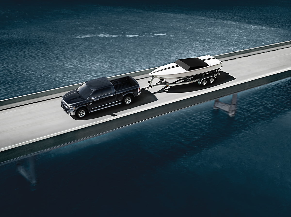 black Ram 1500 towing a boat across a lake bridge