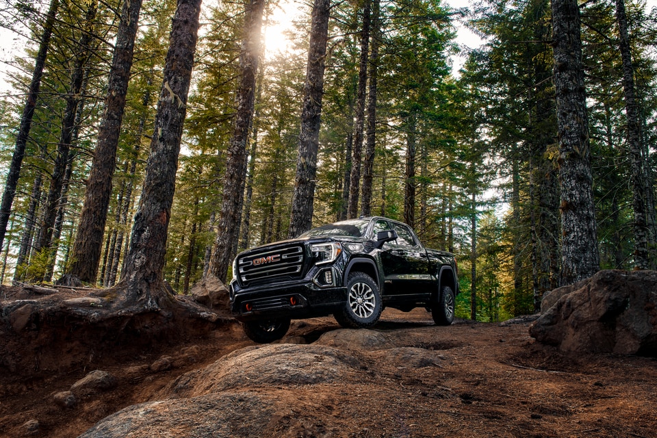black GMC Sierra 1500 truck parked on a rock in a forested area