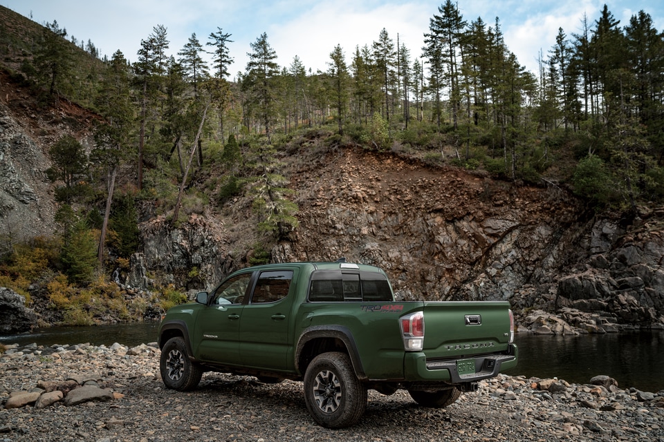 green Toyota Tacoma truck parked in front of a dirt hill, rear and bed featured