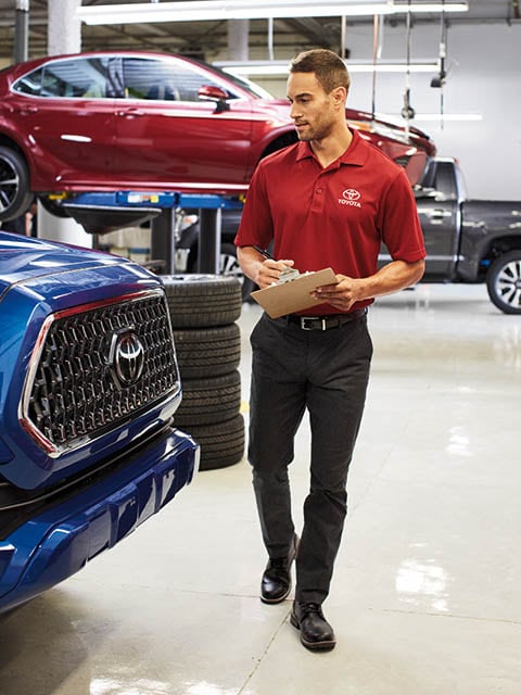 A person walking in a service department inspecting vehicles.
