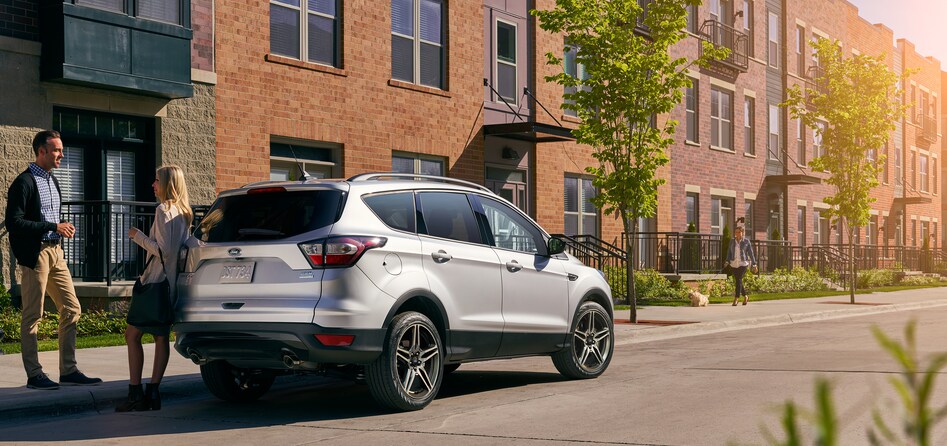 white Ford Escape SUV parked in front of a brick apartment building
