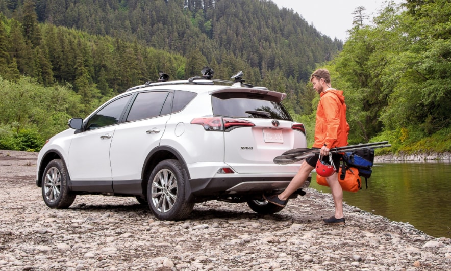 white Toyota RAV4 parked on a river bed, trunk being activated by foot sensor