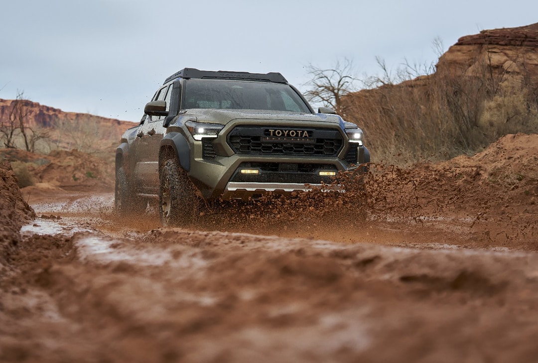 2018-Toyota-Tacoma-TRDSport-DoubleCab-Truck-L01.png blue Toyota Tacoma truck parked at a sand dune with a sport cyclist in the background