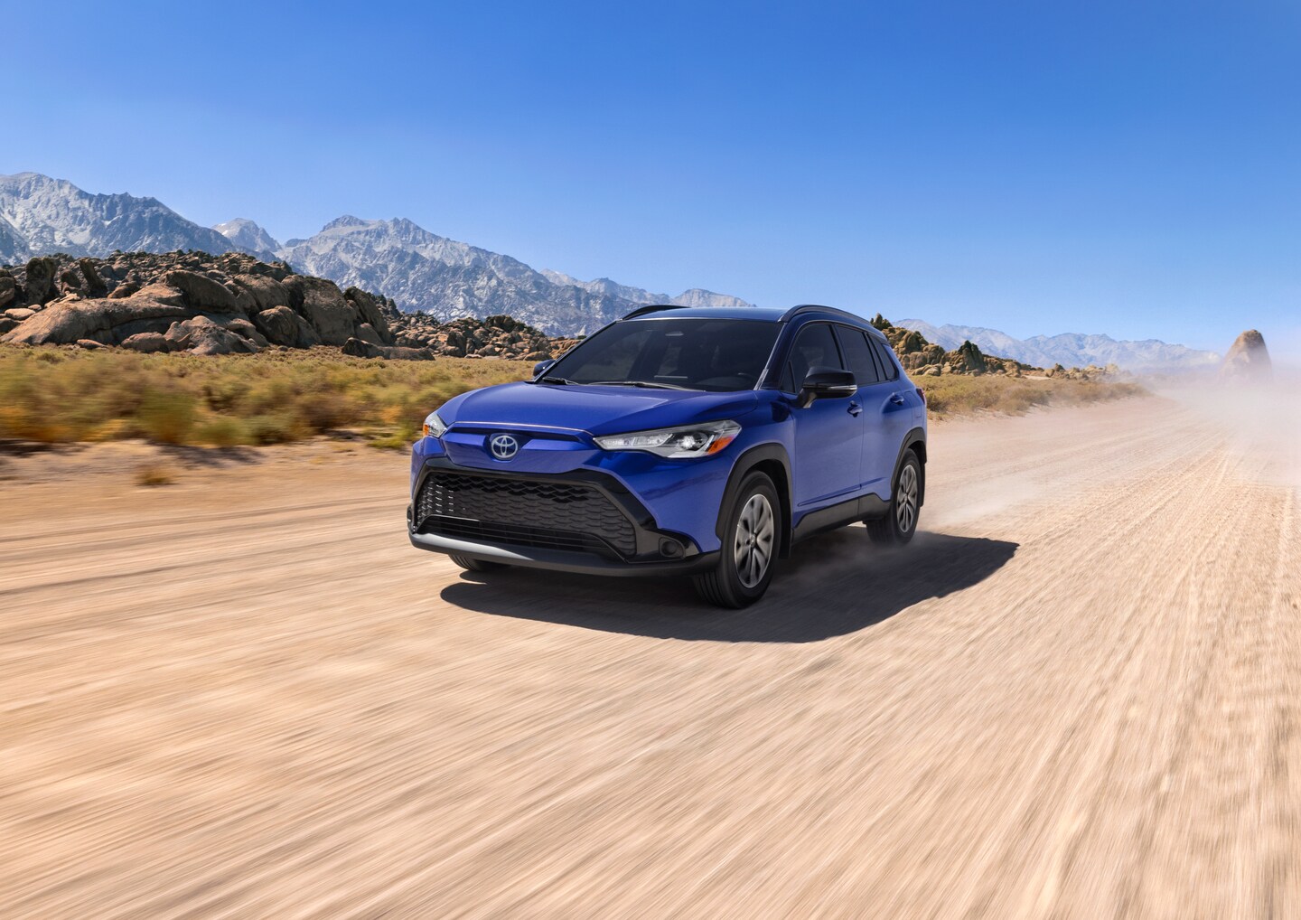 white Toyota Highlander SUV driving through a city with tall buildings on all sides