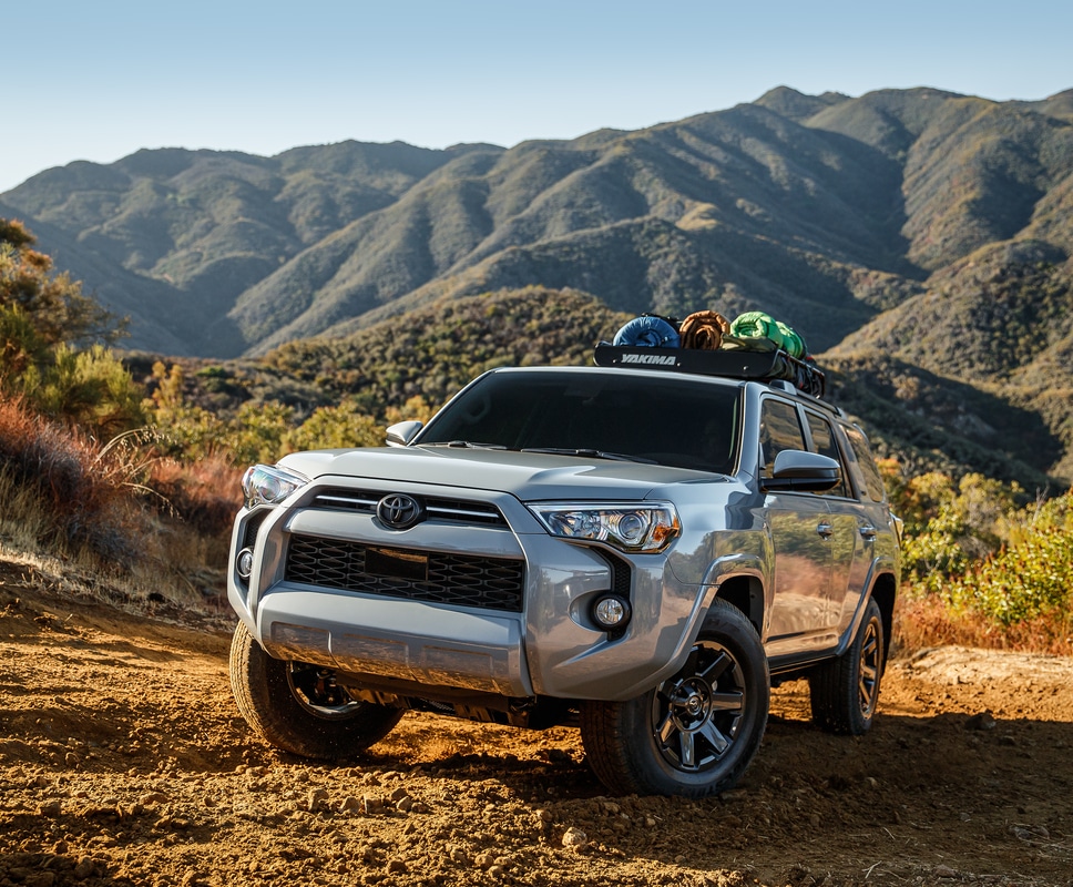 silver Toyota 4Runner SUV parked on a ridge, surrounded by hills