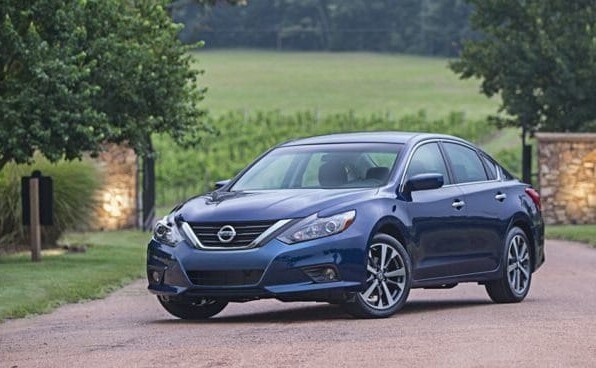 blue Nissan Altima sedan parked in font of a fenced driveway entrance