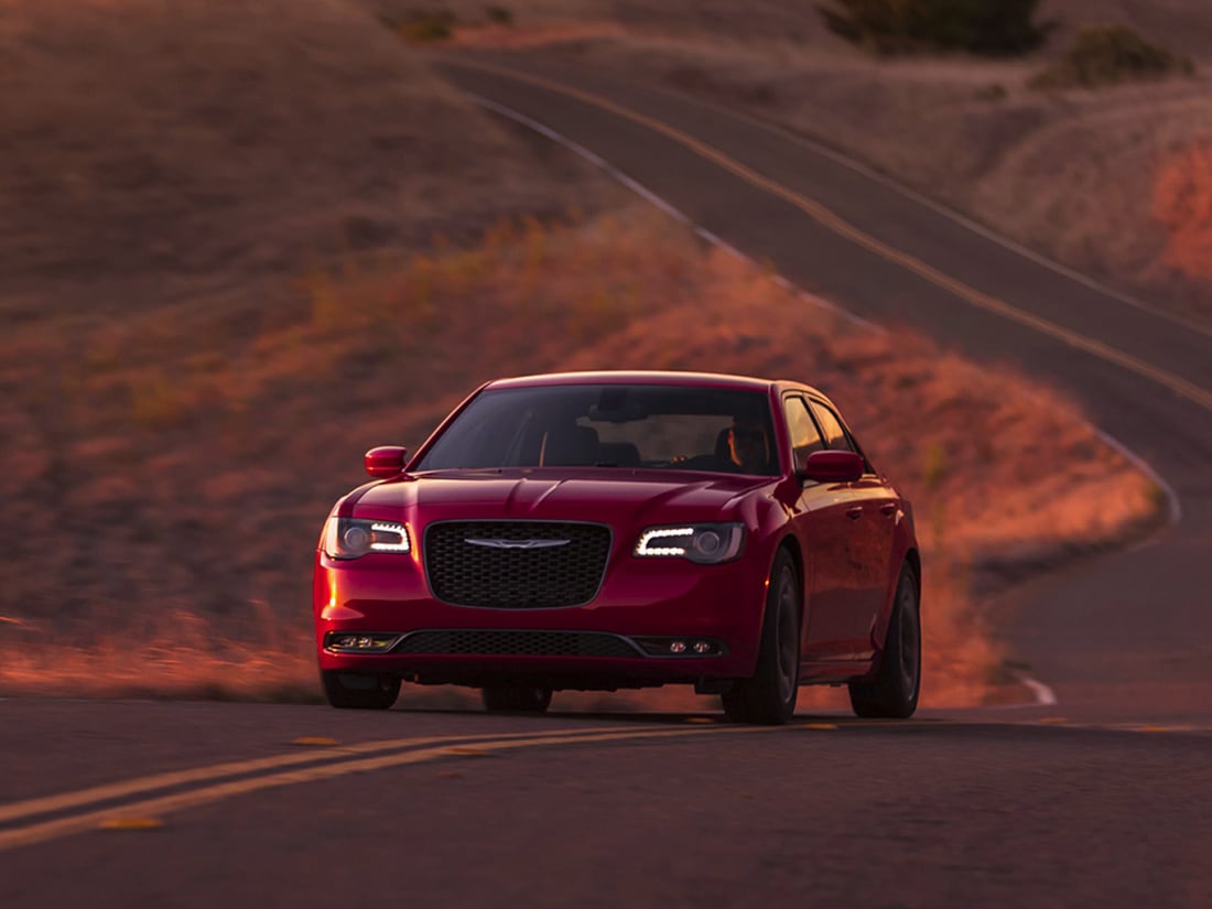 dark red Chrysler 300 sedan driving down a desert highway
