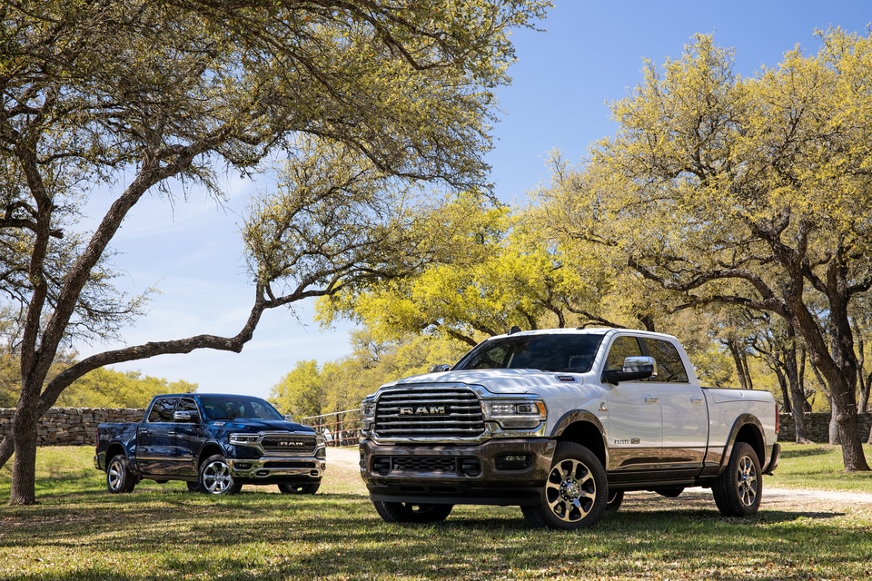 blue and white Ram 2500 Crew Cab trucks parked on green grass, under a tree