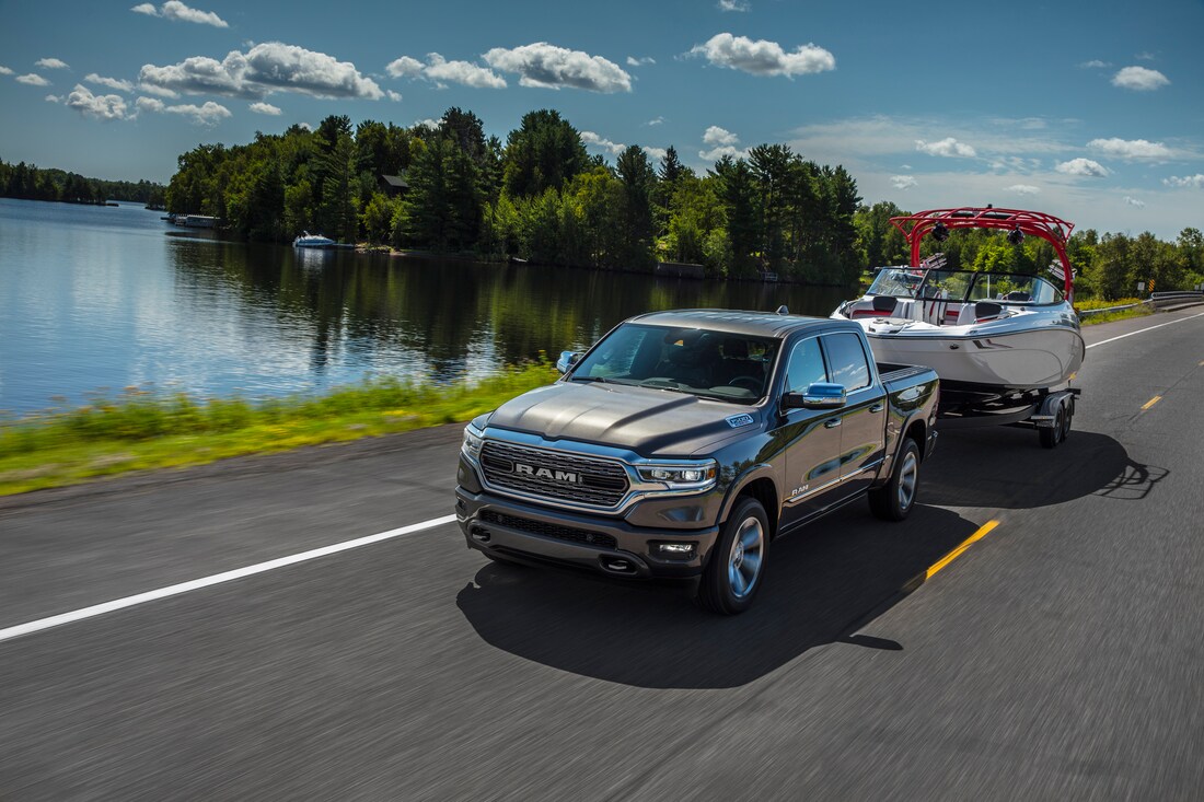 dark gray Ram 1500 Crew Cab truck towing a trailer next to a lake