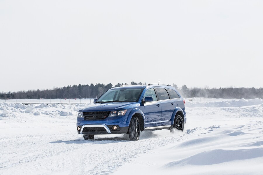 blue Dodge Journey three-row SUV driving through the snow