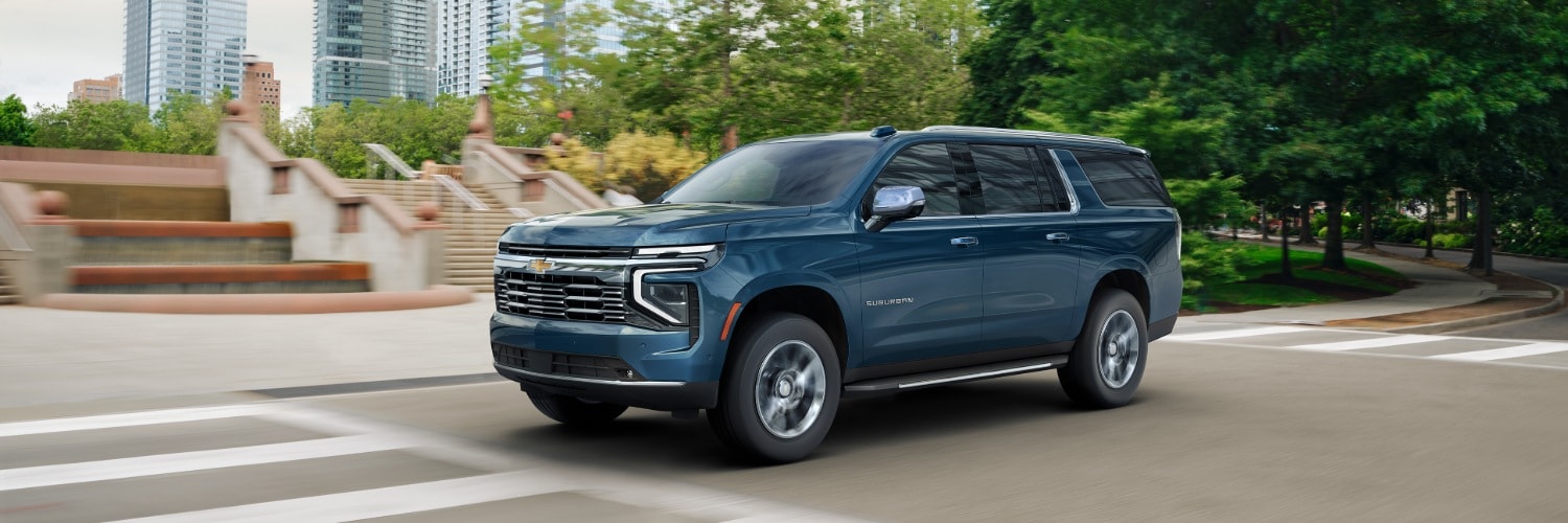 Dark Blue Chevy Suburban driving on a downtown street