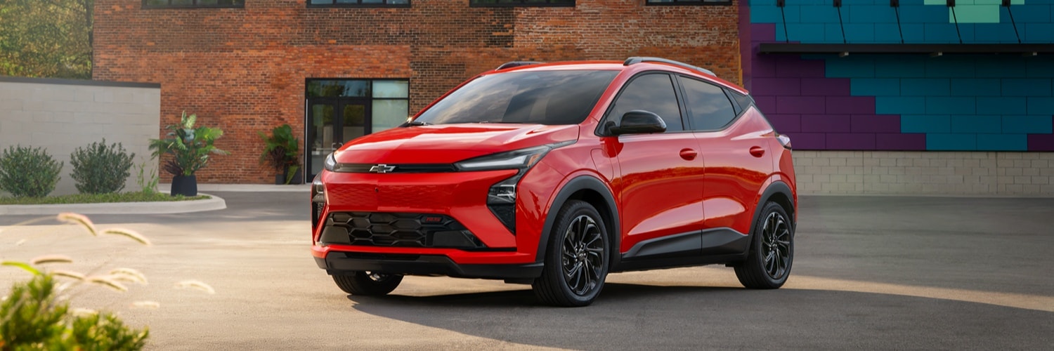 A red Chevrolet Bolt parked in front of a artisticly painted brick building