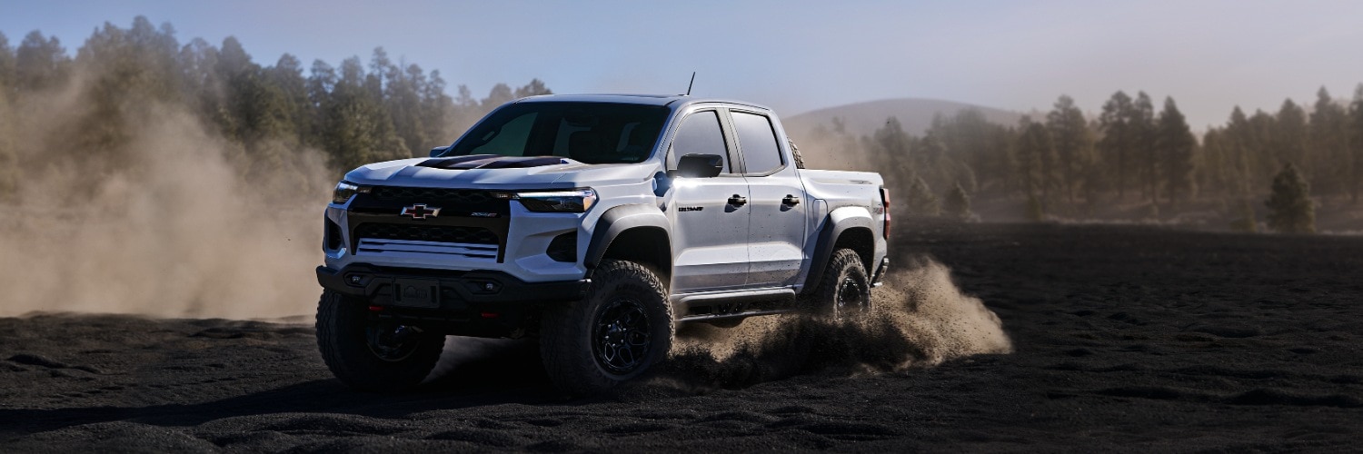 2025 Colorado ZR2 Bison Crew Cab truck driving through black dirt field surrounded by pine trees