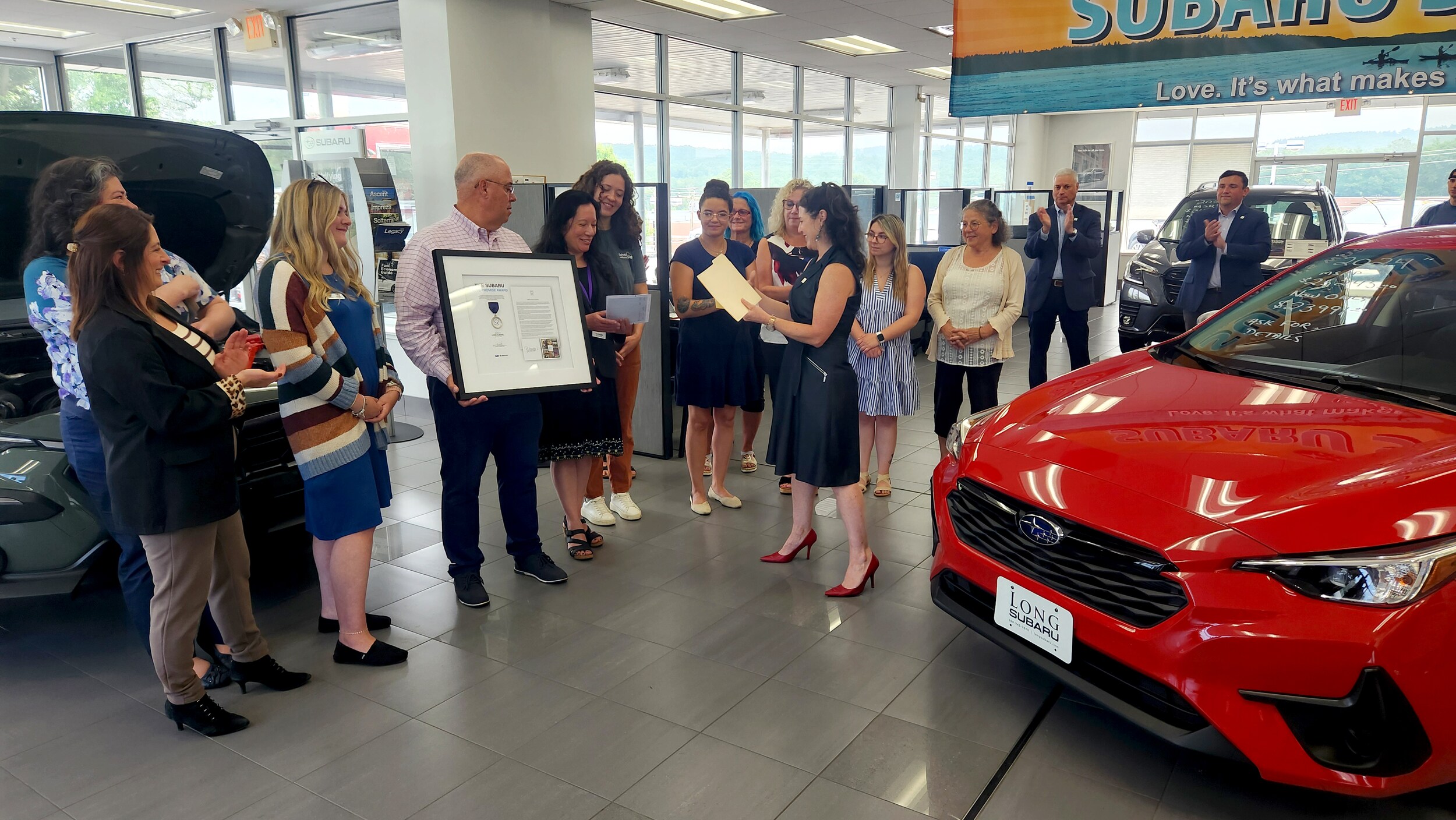 The Long Subaru Team is recieving the award from Rebecca Carr a Subaru of New England Love Promise Manager.