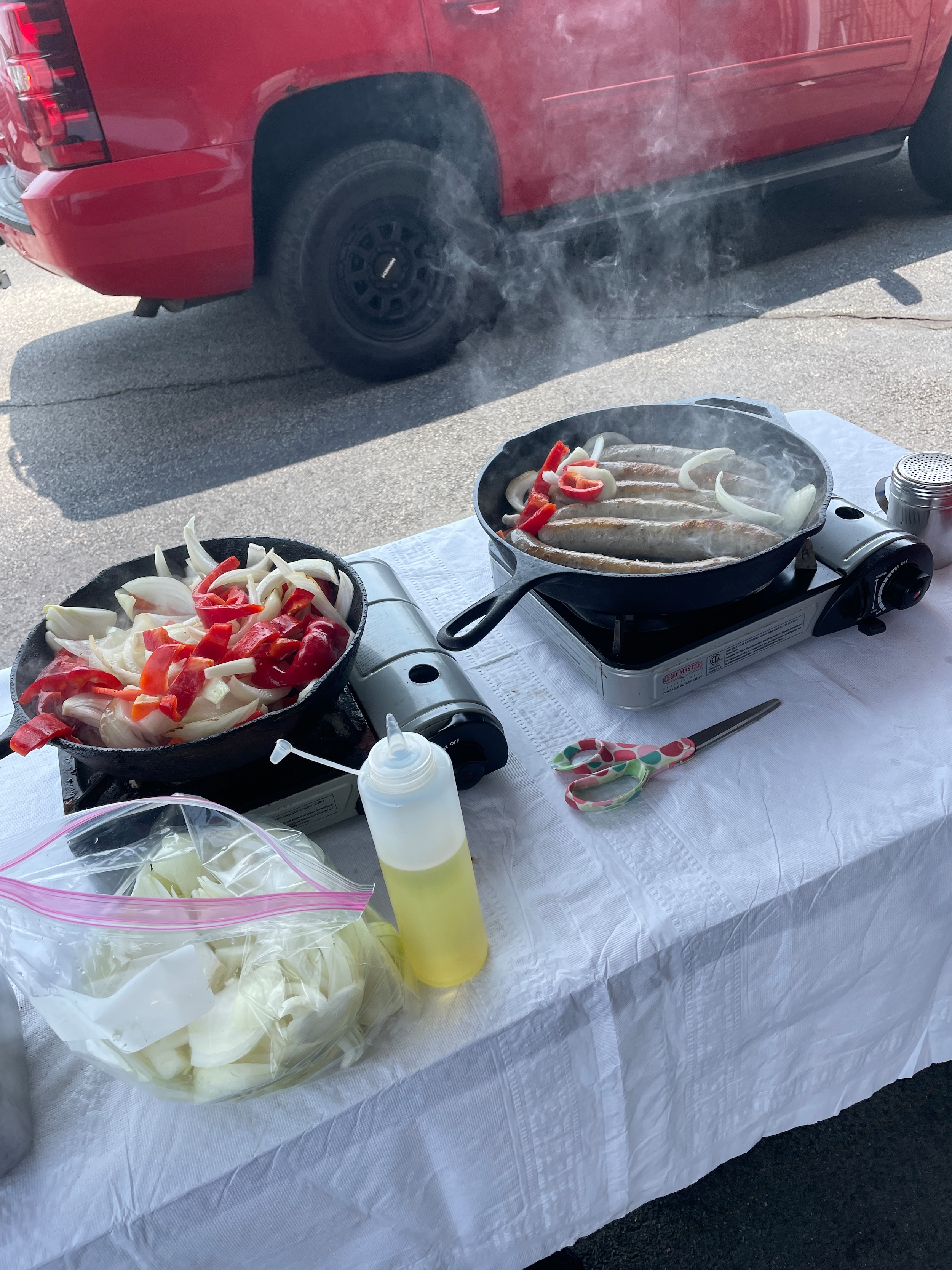 Sausage and peppers and onions being grilled in a cast iron skillet 