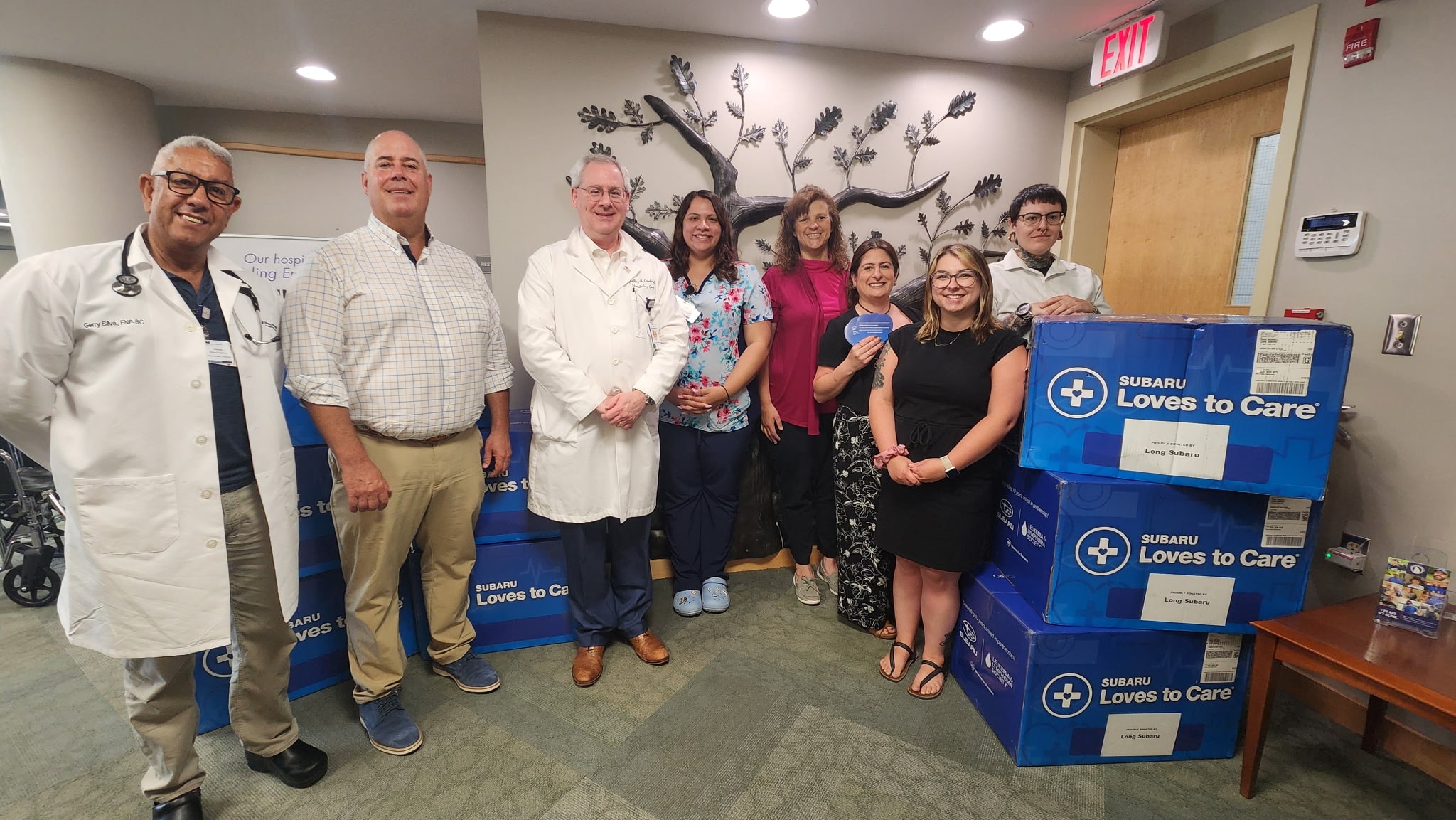 Hospital staff and long subaru employees standing in the hospital with blue boxes full of blankets for Subaru Loves to Care