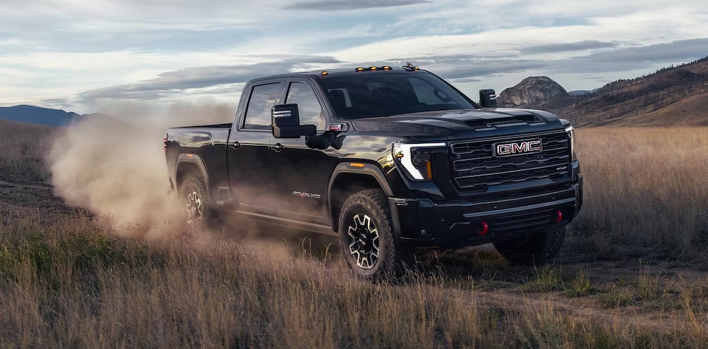2026 GMC Sierra HD driving through dirt road.