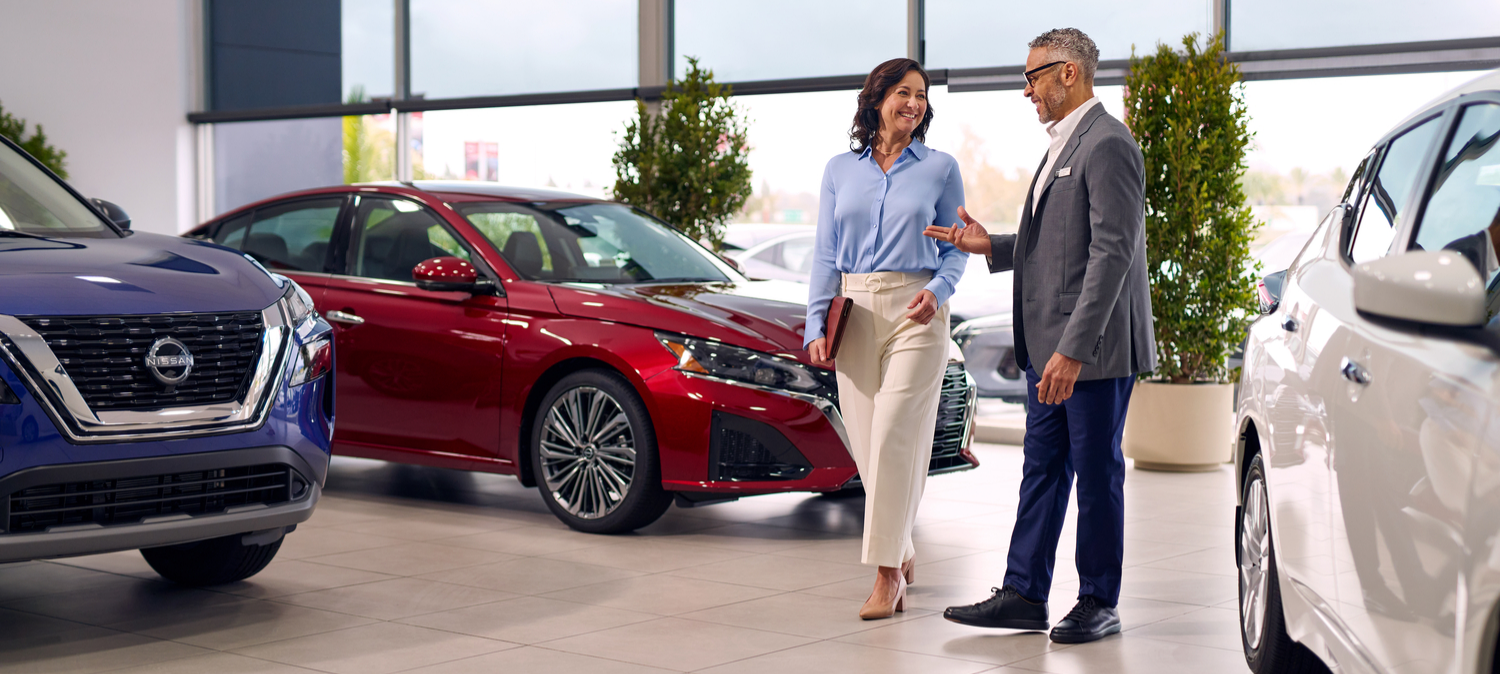 Financing and Leasing Options Customers exploring Nissan financing and leasing options in a dealership showroom with new vehicles on display