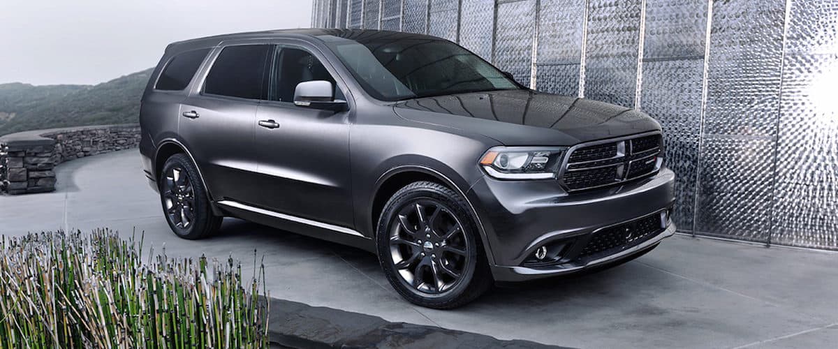 A silver Dodge Durango parked by a concrete wall