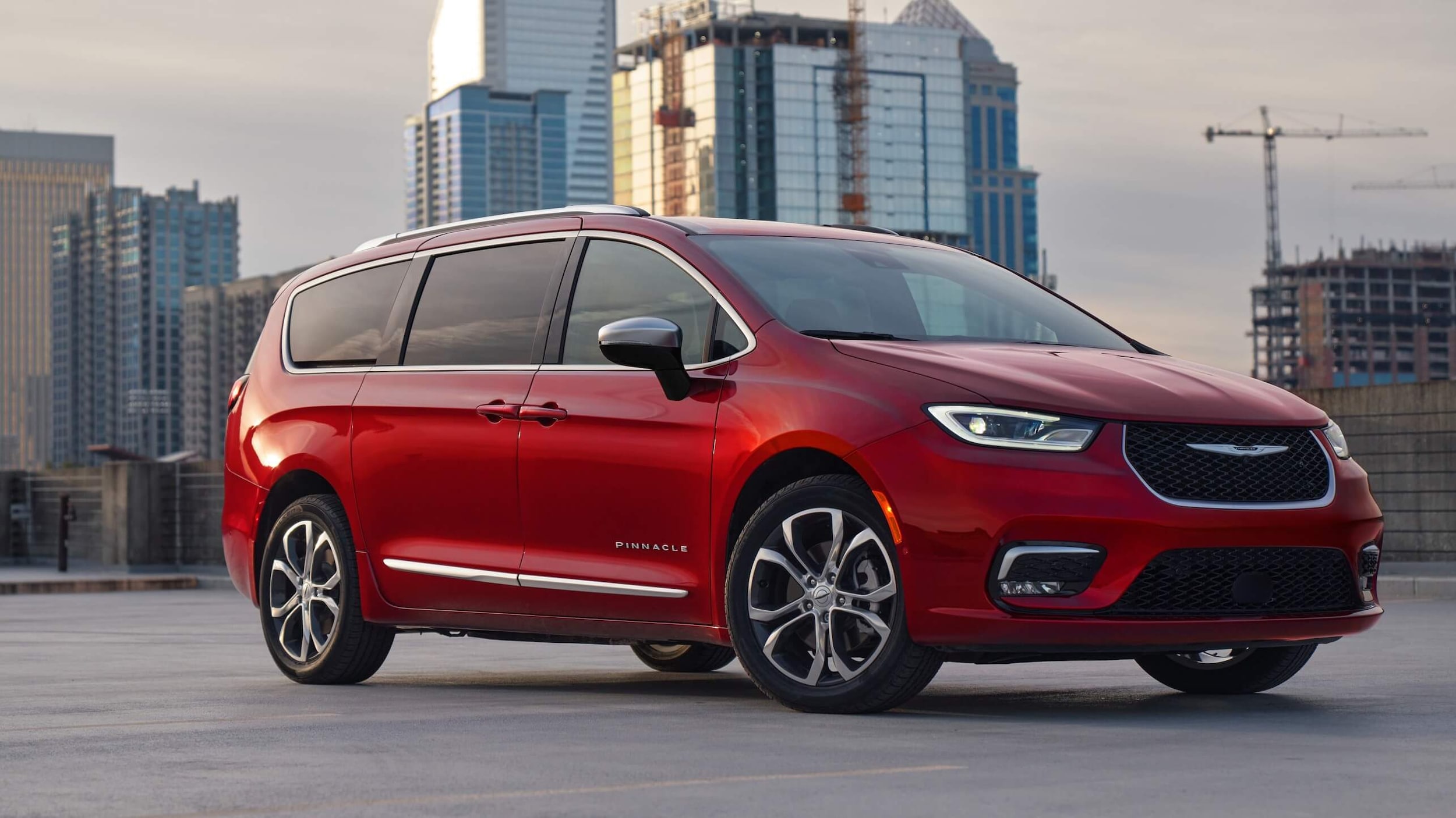 A Chrysler Pacifica parked at a parking garage with a city skyline in the background