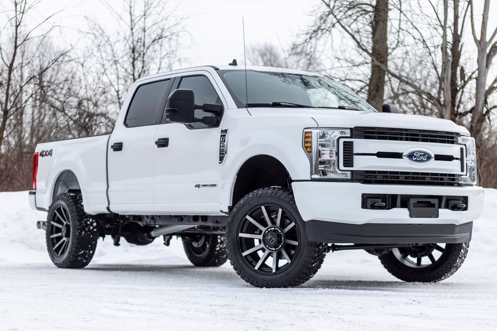White%20Ford%20Super%20Duty%20pickup%20truck%20with%20black%20wheels%20parked%20on%20snowy%20ground%20with%20bare%20trees%20in%20the%20background.jpg