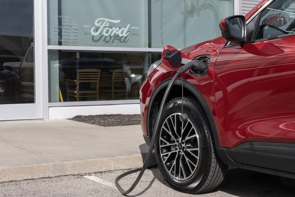 Red%20electric%20vehicle%20plugged%20into%20a%20charging%20station%20outside%20a%20car%20dealership%20building.jpg