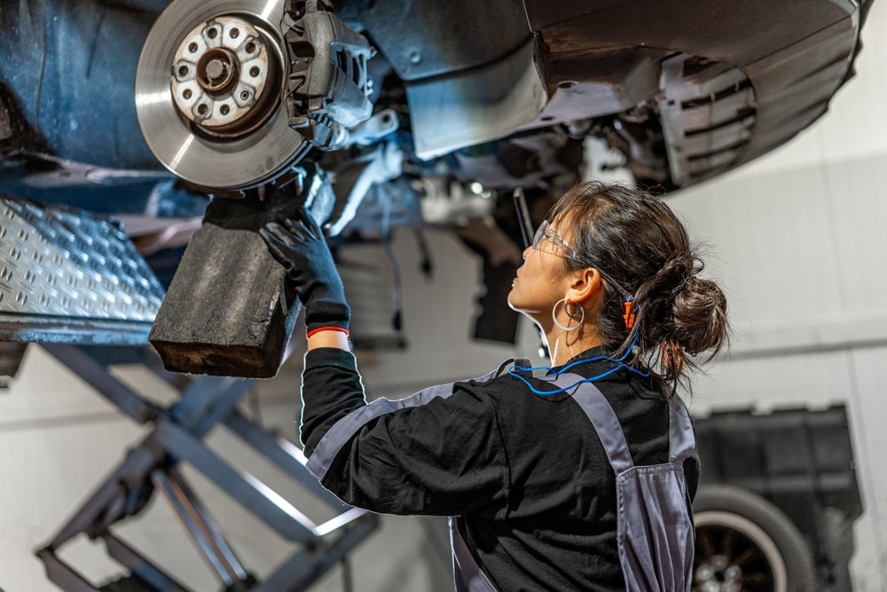 Auto%20mechanic%20inspects%20a%20vehicle%E2%80%99s%20exposed%20brake%20rotor%20and%20caliper%20while%20the%20car%20is%20raised%20on%20a%20hydraulic%20lift.jpg