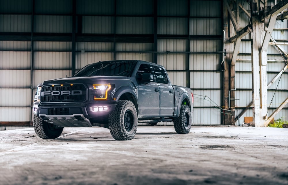 Black%20Ford%20Raptor%20truck%20parked%20inside%20a%20large%20industrial%20warehouse%2C%20with%20rugged%20tires%20and%20headlights%20on%2C%20emphasizing%20its%20off-road%20capability%20and%20bold%20design.jpg