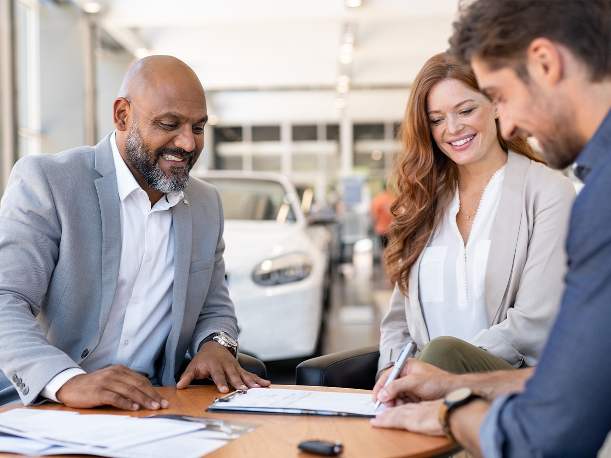 Customers reviewing vehicle purchase paperwork with a dealership representative