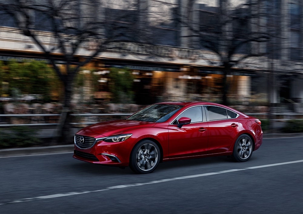 Mazda of New Bern is a car dealership near Pine Knoll Shores NC | Red 2020 Mazda6 driving down city street