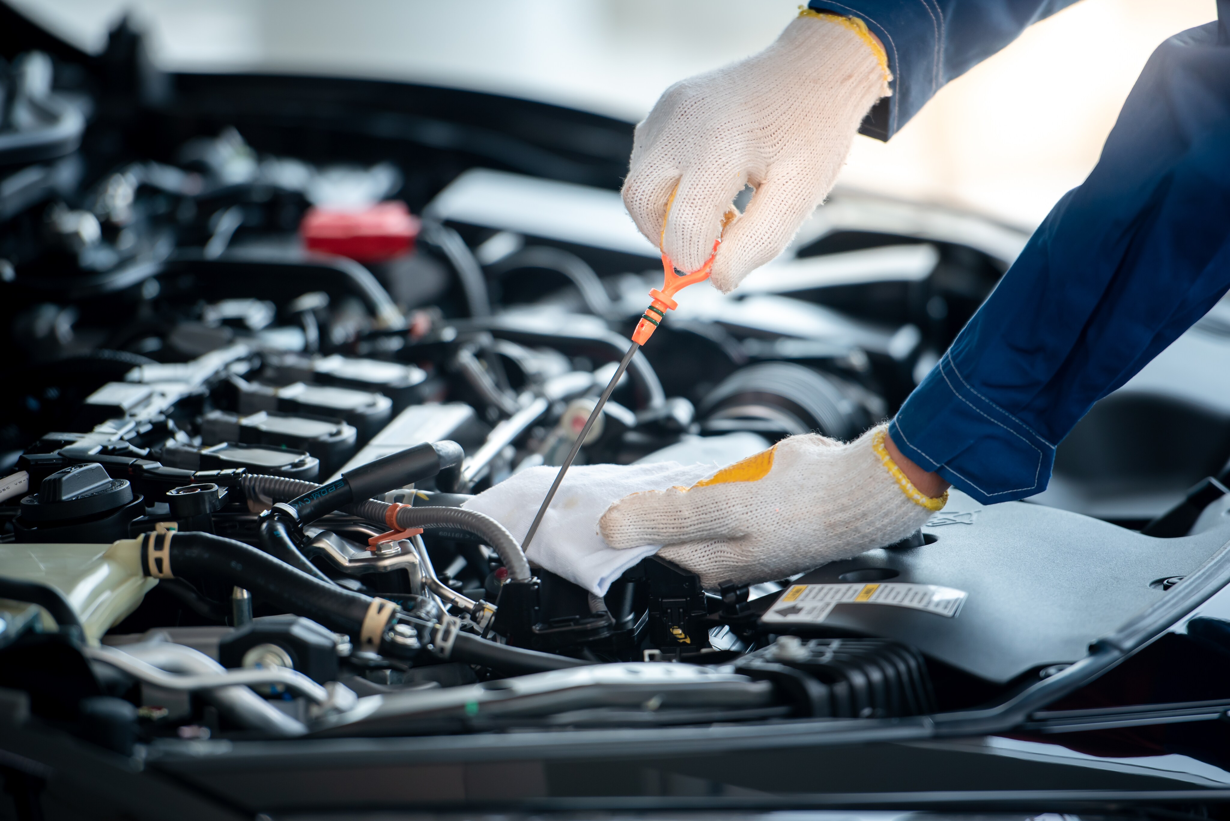 Benefits of Changing Your Mazda's Oil at Mazda of New Bern in New Bern | Mechanic checking oil with dipstick