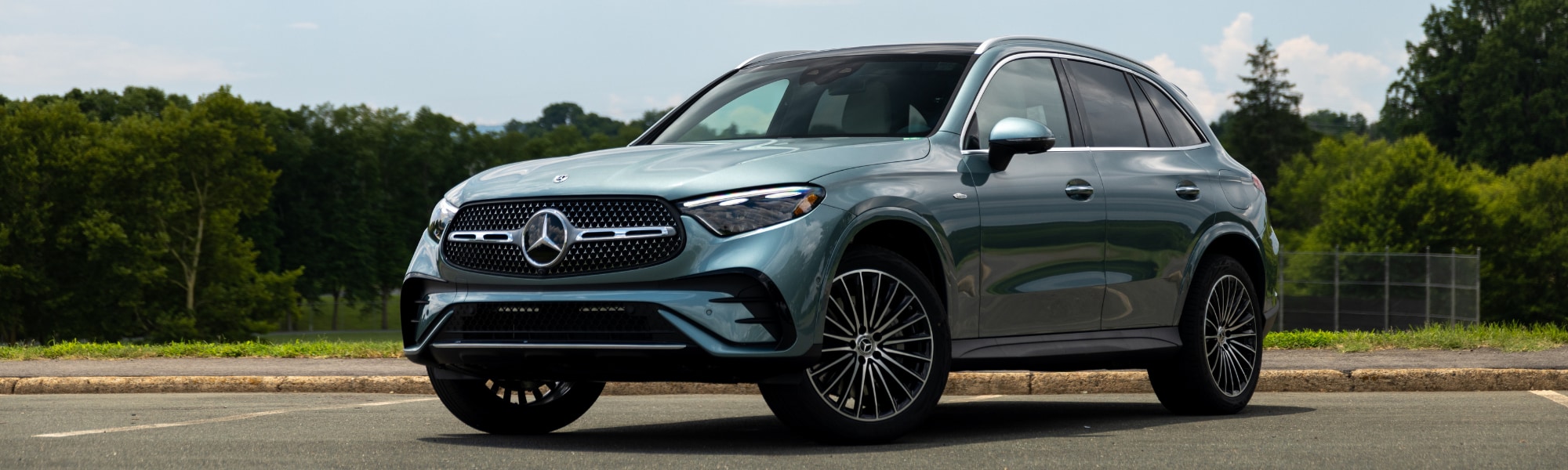 Silver 2025 Mercedes-Benz GLC 350 parked on a paved surface with trees in the background