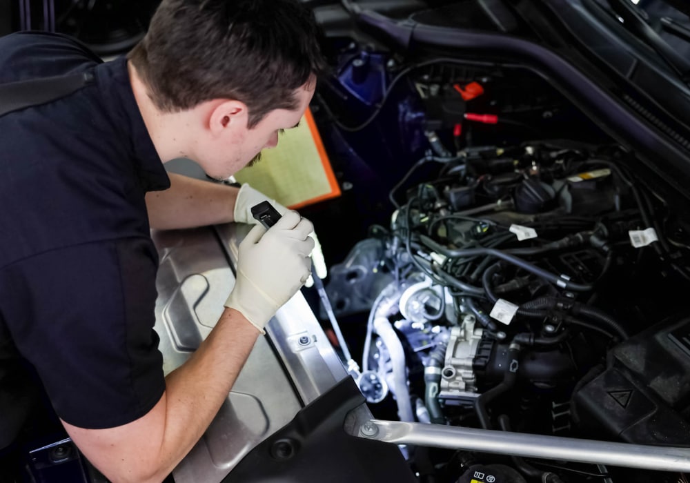 mercedes-cvl-service.png a service technician using a flashlight to look under the hood of a car