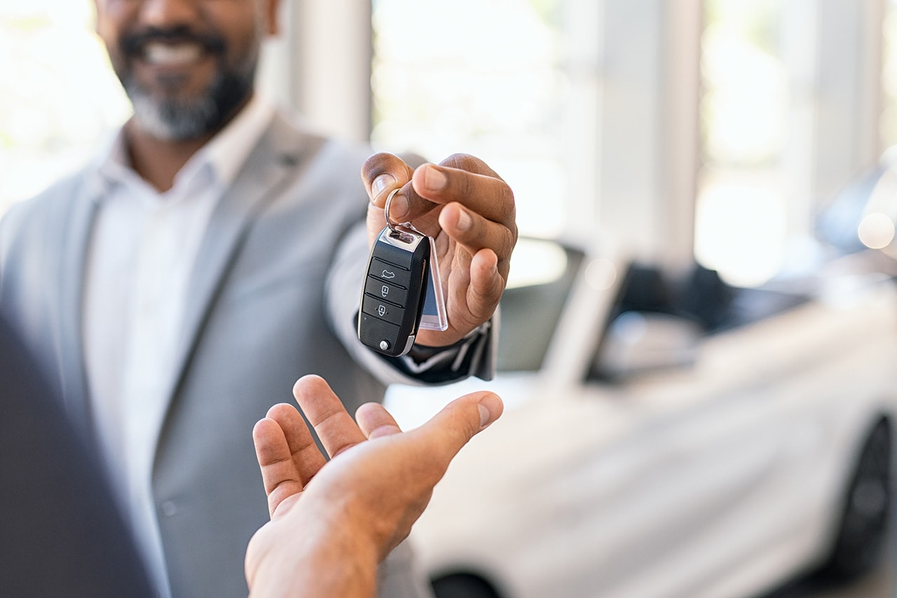 dealer handing keys to a guest with a white convertible